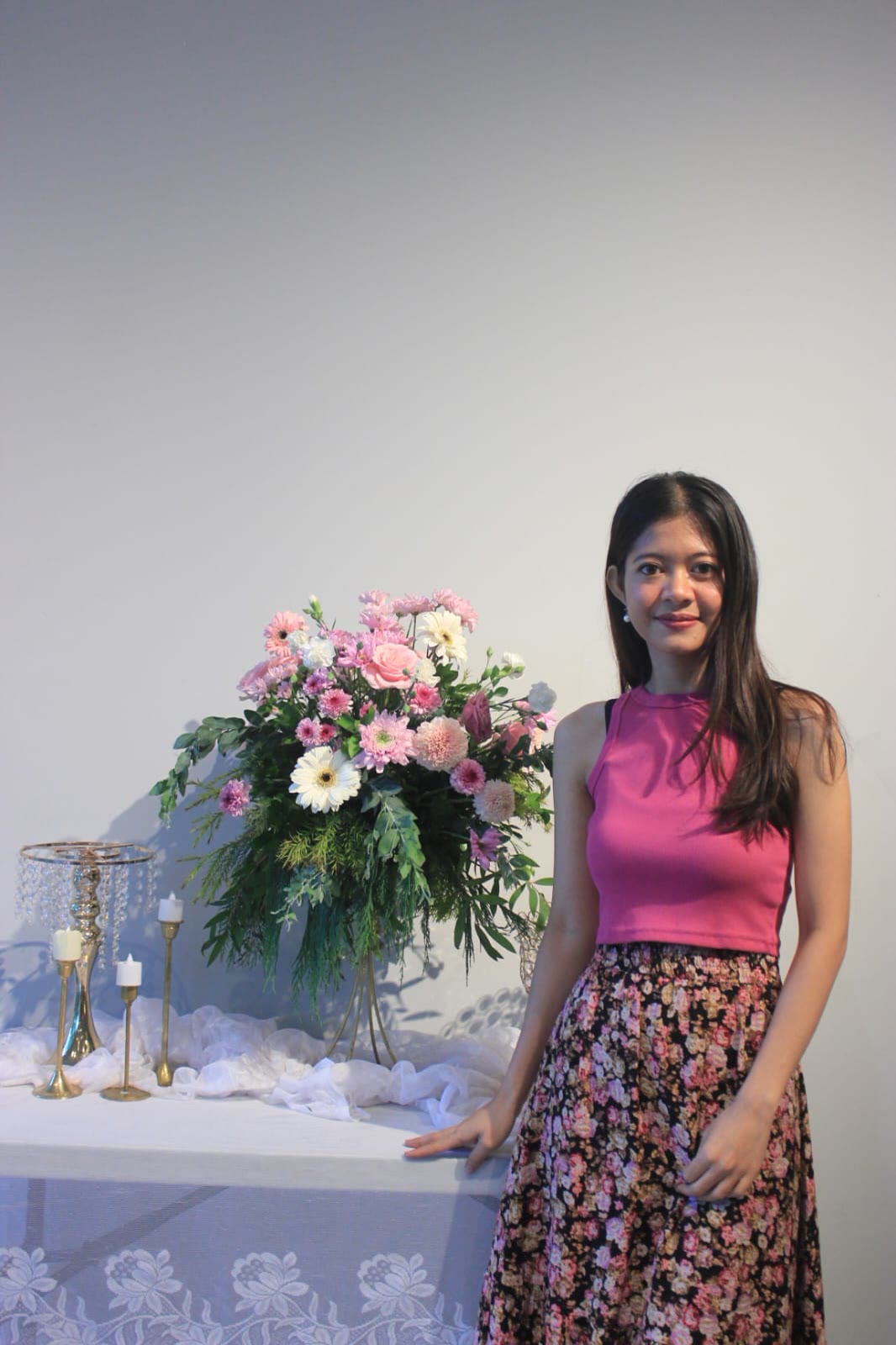 Jemi beside a pink and white flower arrangement